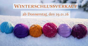 Bunte Wollknauele liegen im Schnee